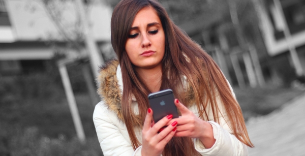 Mädchen schaut auf das Handy, das sie in der Hand hält